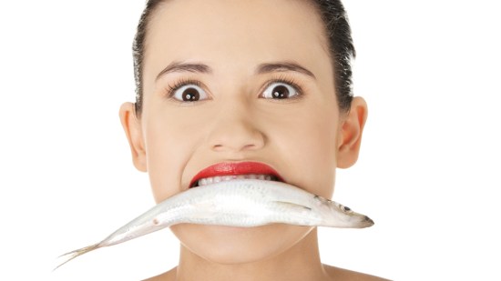mujer con un pescado en la boca