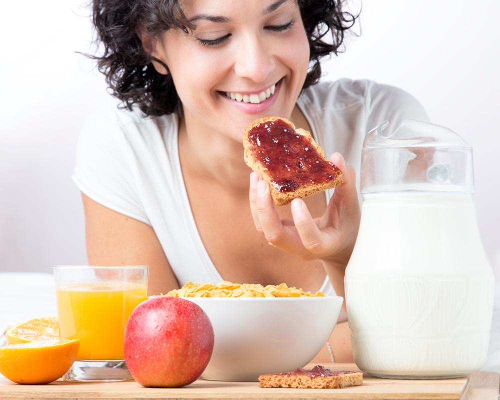 chica tomando un tostada de pan con mermelada