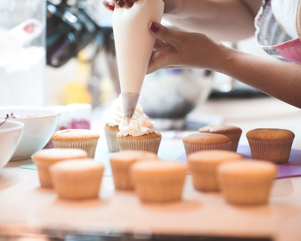 mujer con una manga pastelera cubriendo una magdalena
