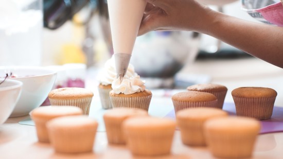 mujer con una manga pastelera cubriendo una magdalena
