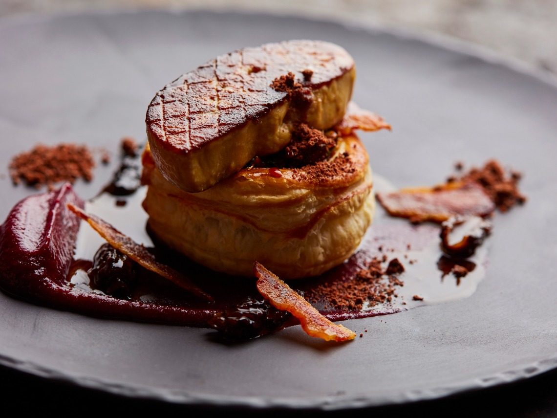 primer plano de hojaldre con foie sobre fondo negro