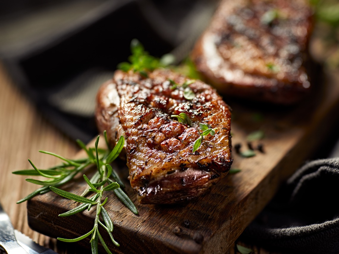 magret de pato con hierbas sobre tabla de madera y fondo negro