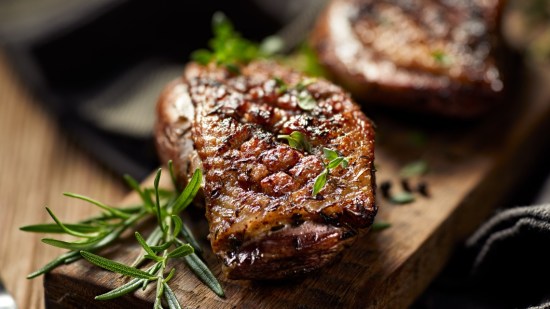 magret de pato con hierbas sobre tabla de madera y fondo negro