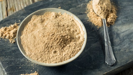 maca en polvo en cuenco blanco y cuchara sobre mesa negra