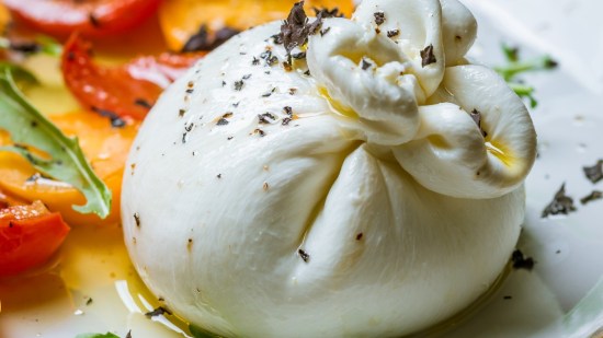 burrata con tomate y albahaca sobre plato blanco primer plano