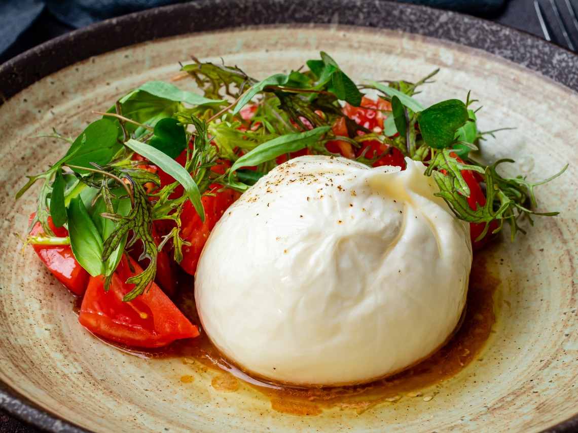 burrata con verduras sobre plato blanco