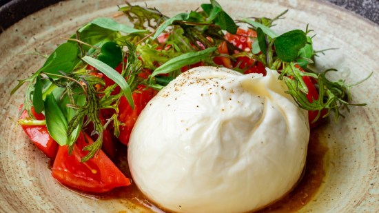 burrata con verduras sobre plato blanco