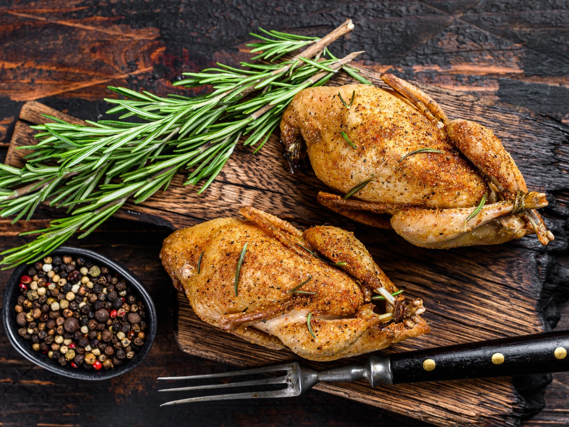 plano zenital dos codornices con ramita de romero sobre mesa de madera