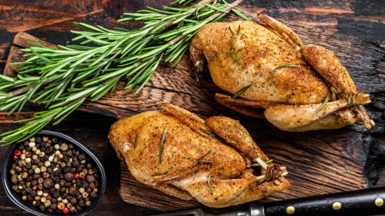 plano zenital dos codornices con ramita de romero sobre mesa de madera