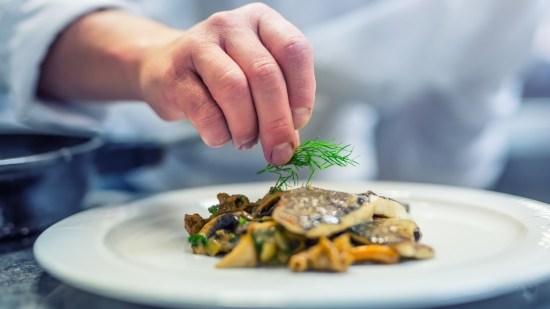 mano de cocinero terminando un plato de pescado alta cocina
