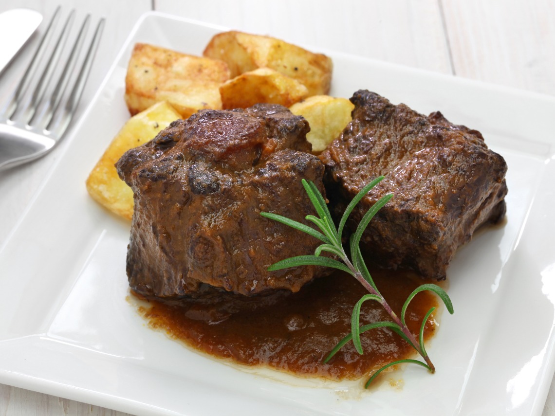 rabo de toro guisado con patatas sobre plato blanco