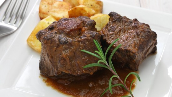 rabo de toro guisado con patatas sobre plato blanco
