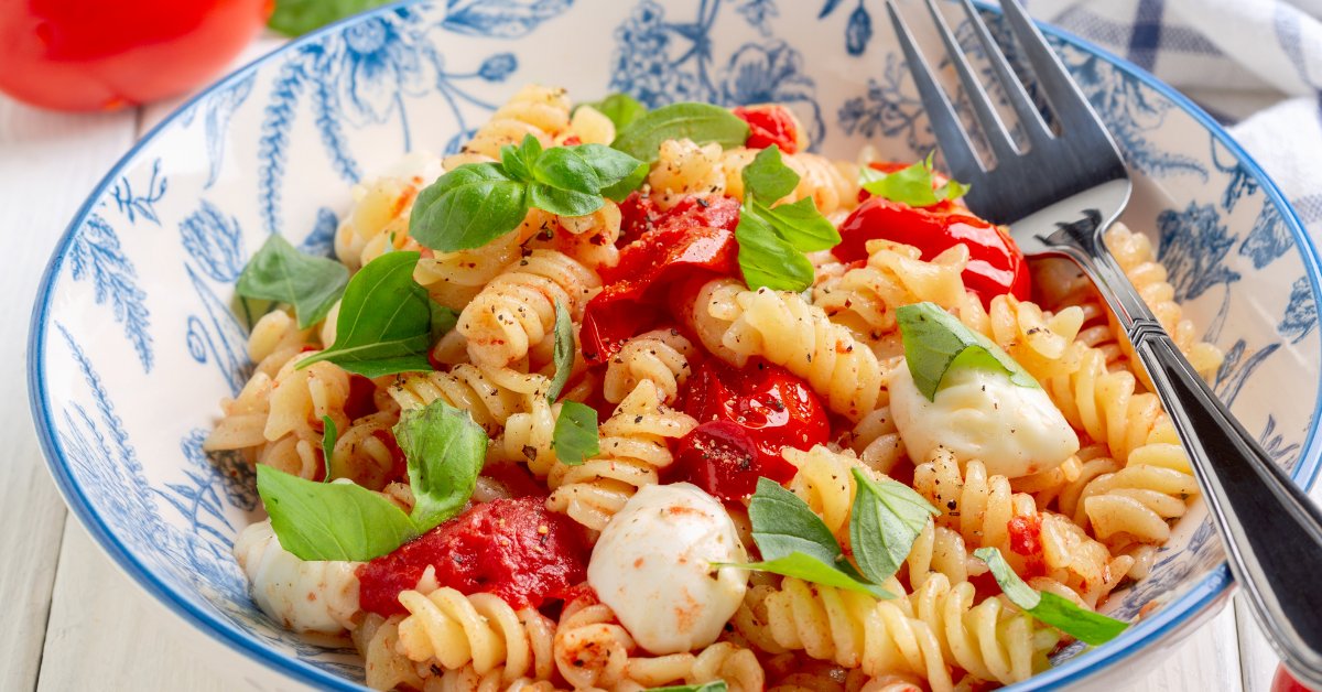 Ensalada caprese de pasta corta con perlas de mozzarella y albahaca fresca