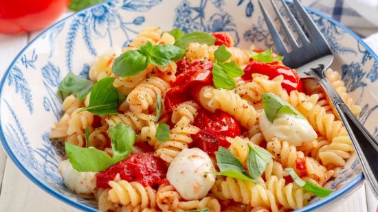 Ensalada caprese de pasta corta con perlas de mozzarella y albahaca fresca