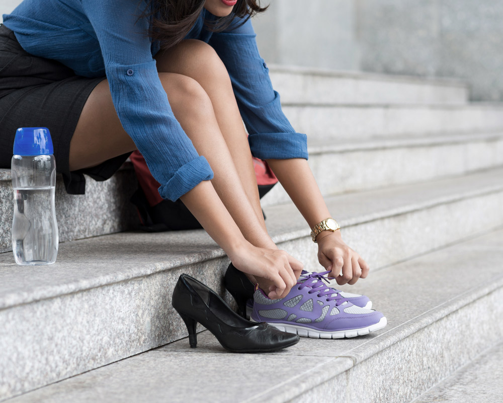 Mujer cambiandose los zapatos por zapatillas para correr.