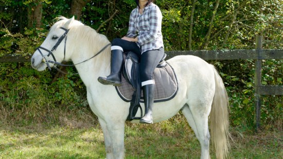 Mujer montando a caballo.