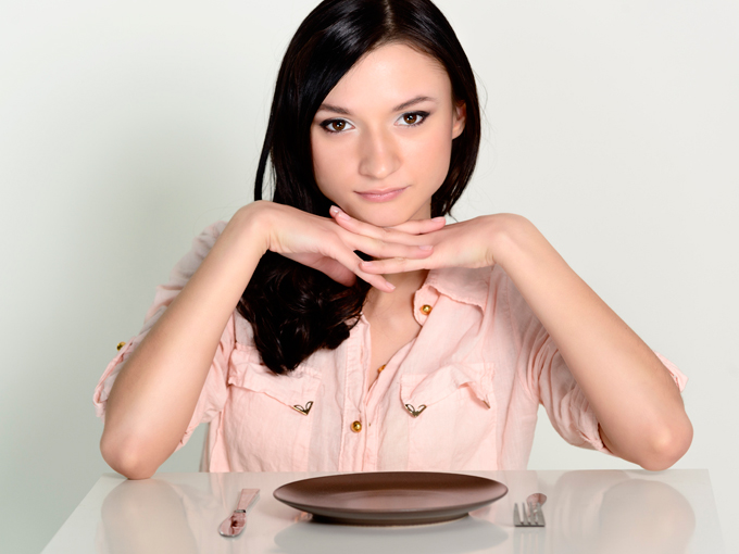 Mujer con los codos apoyados en la mesa.