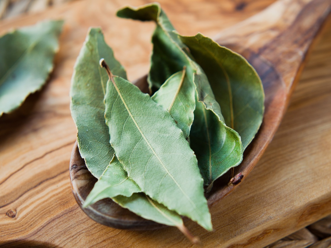 hojas de laurel secas en cucharon de madera sobre mesa de madera