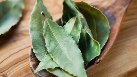 hojas de laurel secas en cucharon de madera sobre mesa de madera