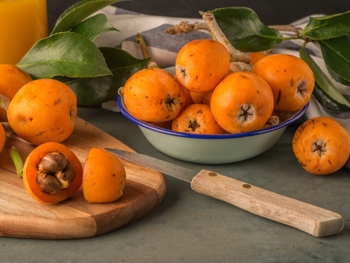 nisperos sobre tabla de madera y frutero