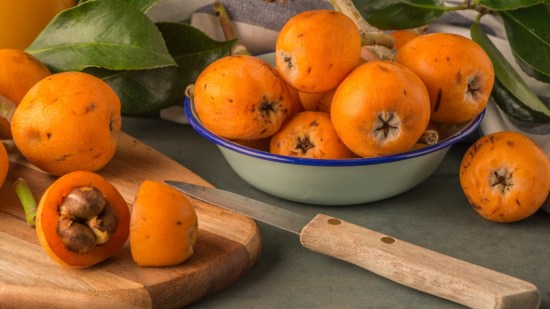 nisperos sobre tabla de madera y frutero