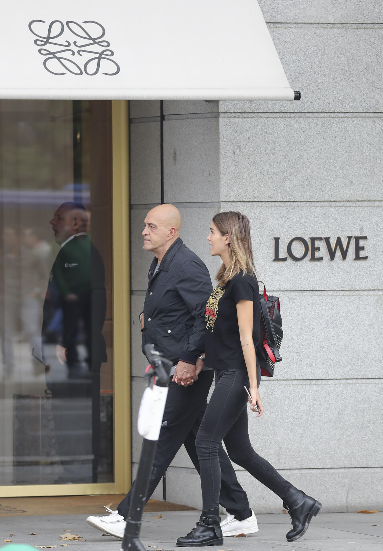 Personas caminando frente a una tienda de Loewe, con un diseño minimalista en su fachada.